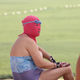 A masked female holidaymaker looks on at a beach resort on a scorching day in Qingdao city, east Chinas Shandong province, 3 July 2013. Holidaymakers are flooding to the beach resorts to cool down in the eastern Chinese coastal city of Qingdao as heat waves are sweeping through many parts of China. A group of female swimmers are spotlighted among the others as they dress their heads up with colorful masks, making them look like masked robbers or terrorists. Dubbed as the bikini for faces, the mask is used to protect the face of its user from being tanned by scorching sunlight and stung by jellyfish. Priced at 15-20 yuan (US$2.44-US$3.26) apiece, the mask is quite popular among middle-aged and elderly women.(Imaginechina via AP Images